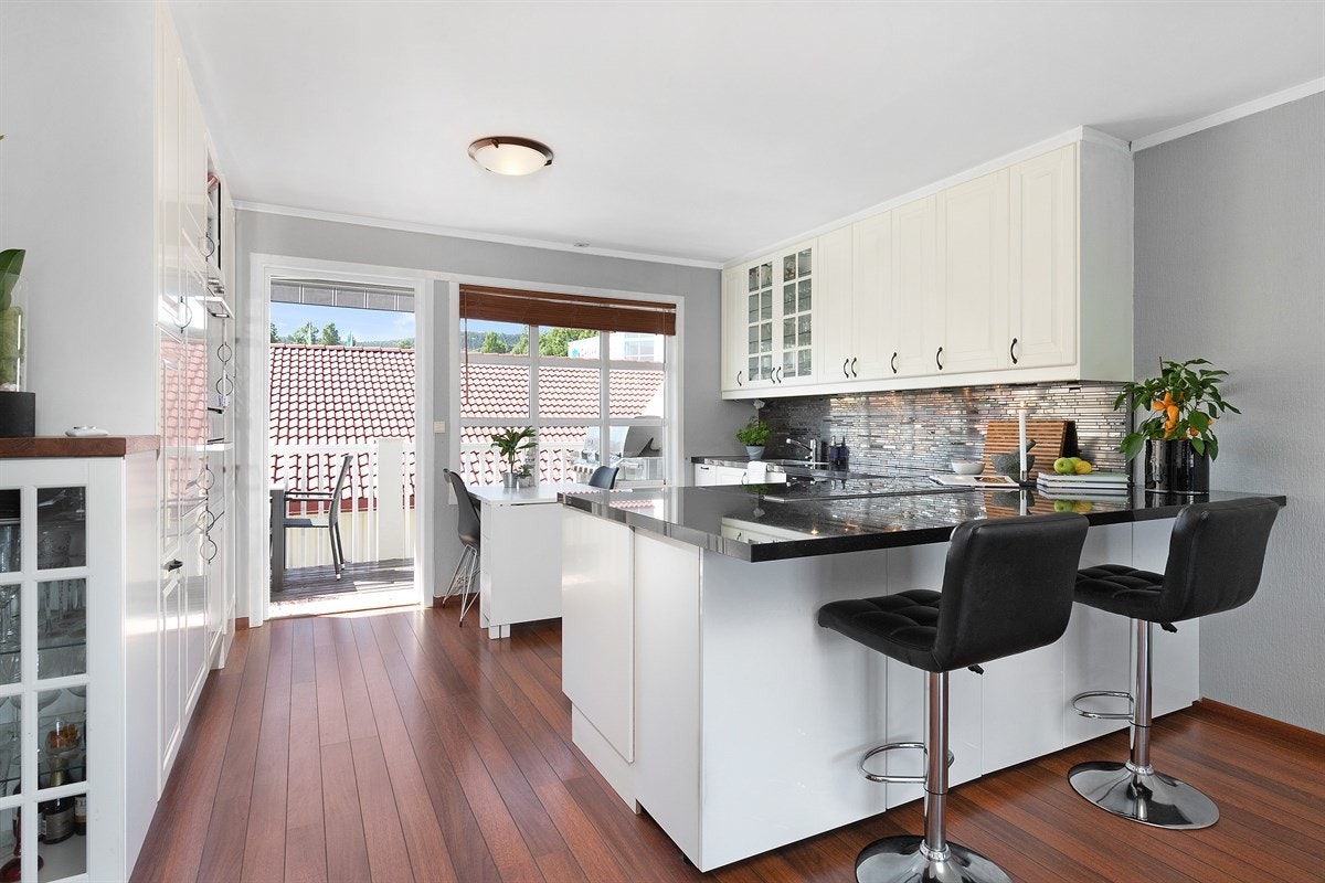 Kjøkkeninnredningen har et tidløst design med hvite, profilerte fronter, takhøye skap og ny benkeplate i granitt med underlimt oppvaskkum i stål. Galleribilde