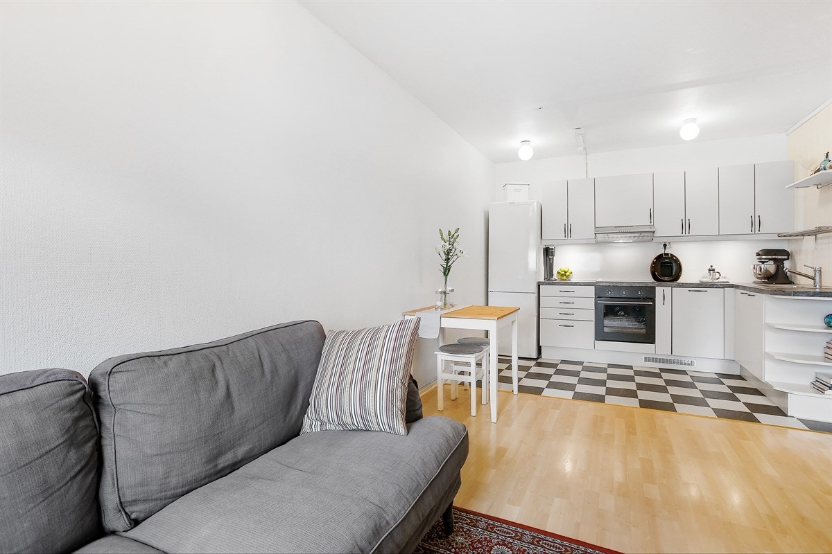 Praktisk åpen kjøkkenløsning med innredning i hvit utførelse samt laminat benkeplate. Galleribilde