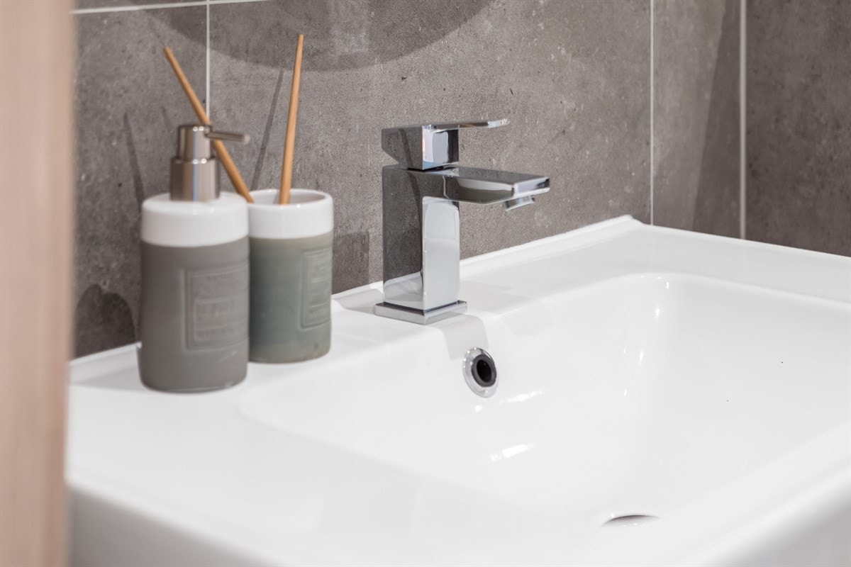 Badet inneholder dusjhjørne, servantinnredning med tilhørende underskap og speil over, vegghengt toalett samt varmtvannsbereder (i skap). Galleribilde