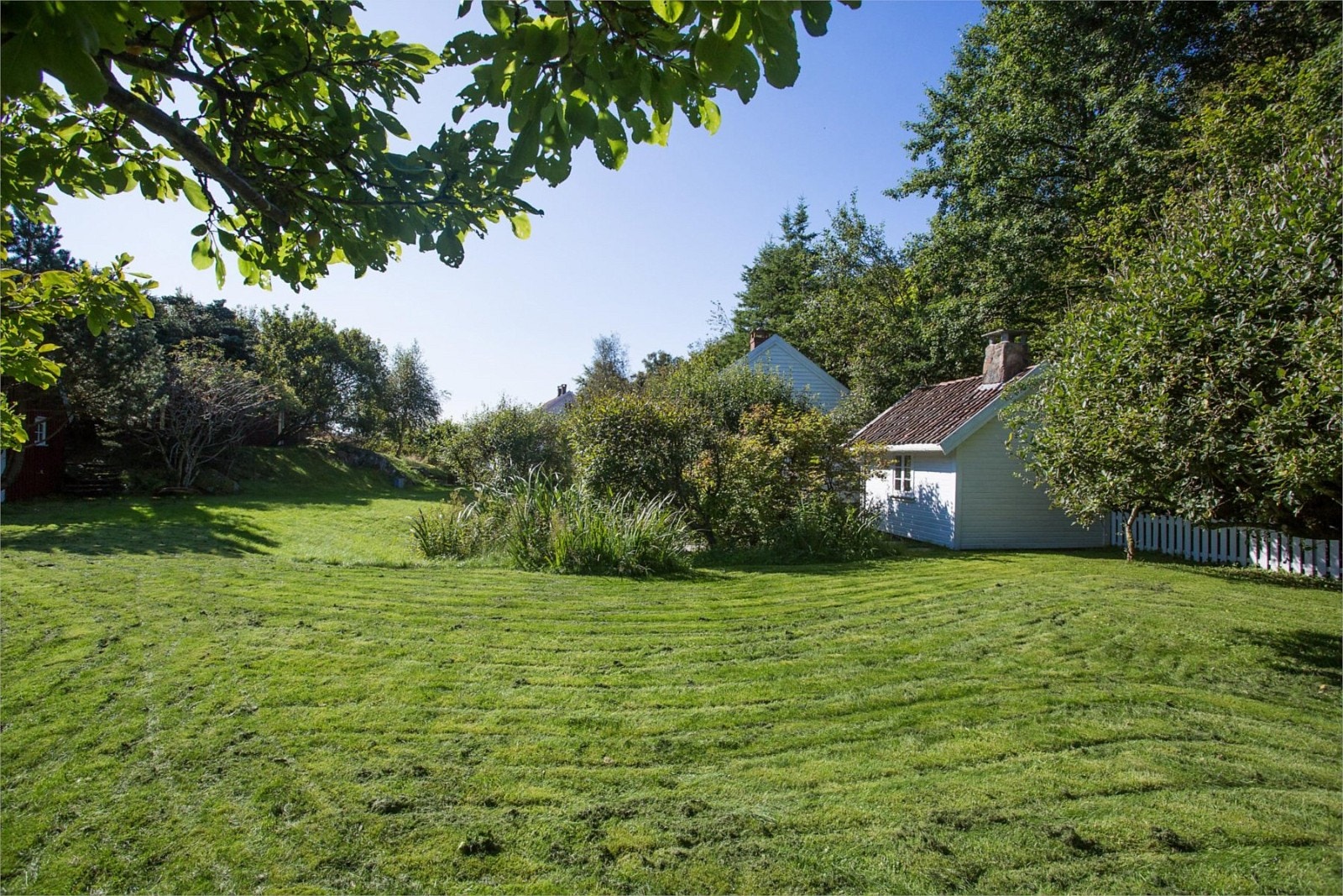 Usjenert og flott opparbeidet hage. Verehuset ses til høyre. Galleribilde