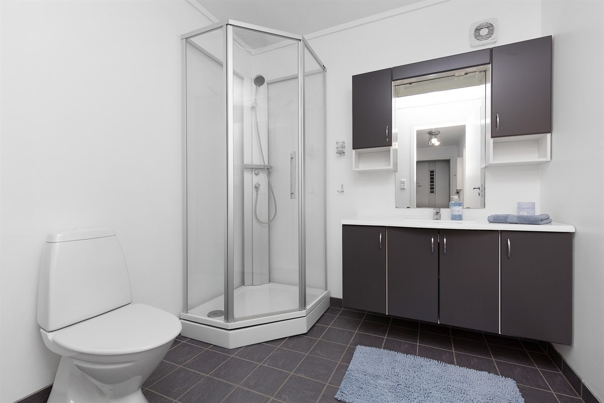 Bad med fliser på gulv og varmekabler, samt dusjkabinett... Galleribilde