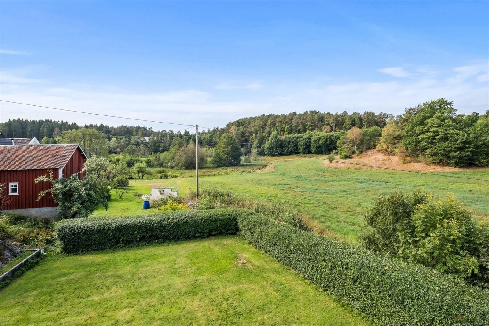 Hagen er pent opparbeidet med plen, rammet inn av velstelt hekk. Galleribilde