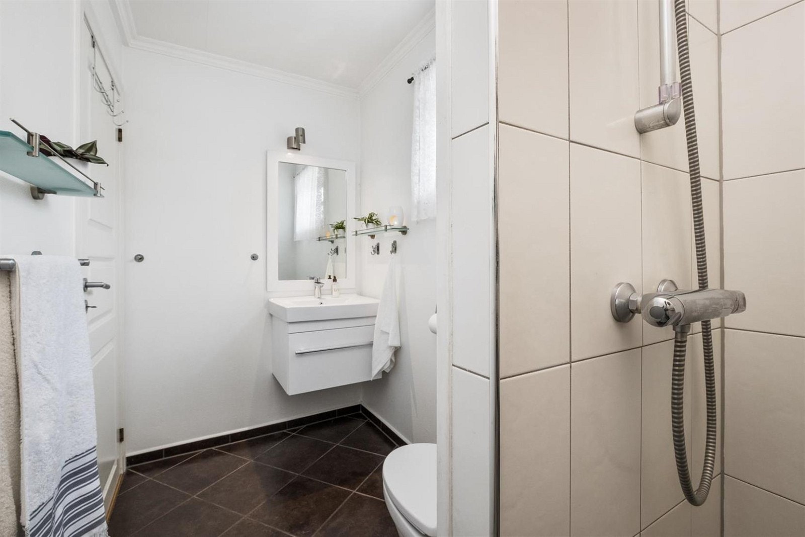 Bad 1.etg. . Badet har mørke fliser pågulv, lysmalte vegger og veggfliser på i dusjnisjen. Galleribilde