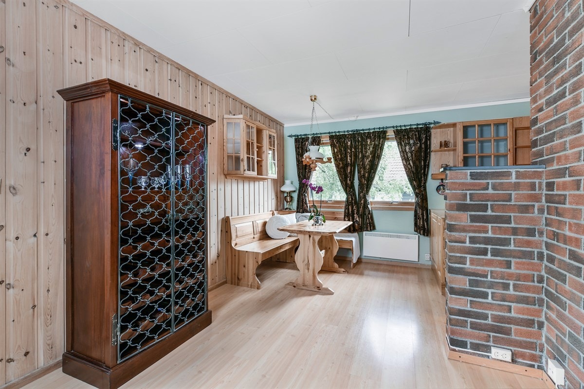 Ved kjøkkenet er en hyggelig spiseplass, innredet med hjørnebenk, bord og vitrineskap. Galleribilde