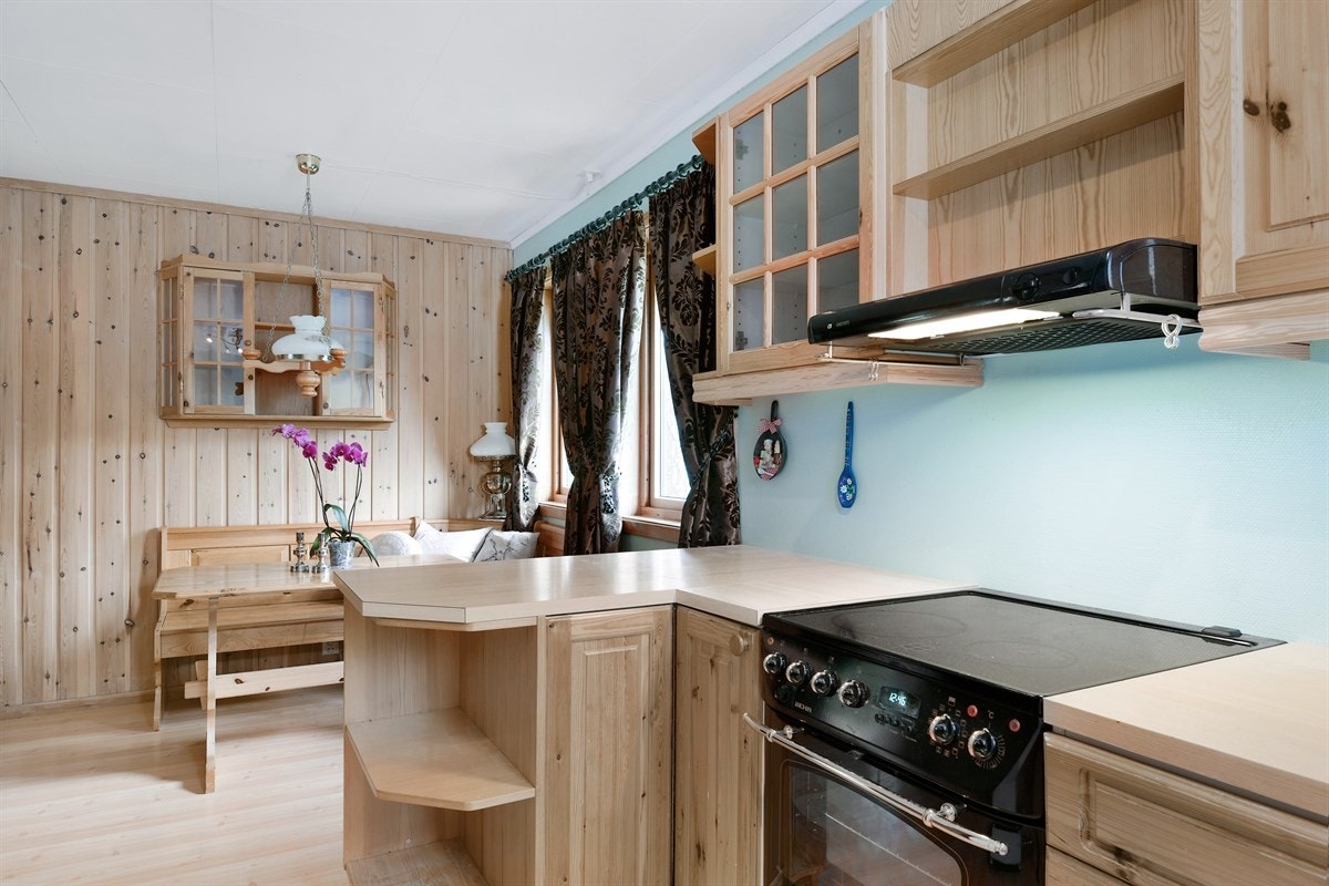 Over benken er det belysning. Innredningen består av overskap, hyller, benkeskap, skuffer og høyskap, og det er barløsning mot spiseplassen. Galleribilde