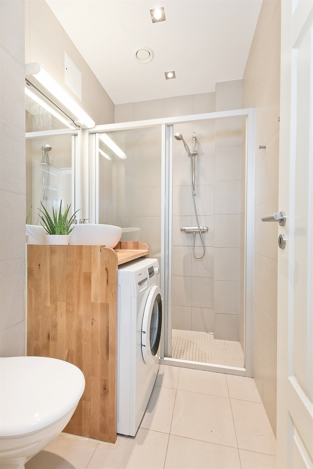 Pent flislagt bad med vegghengt toalett, servant og dusjhjørne. Galleribilde