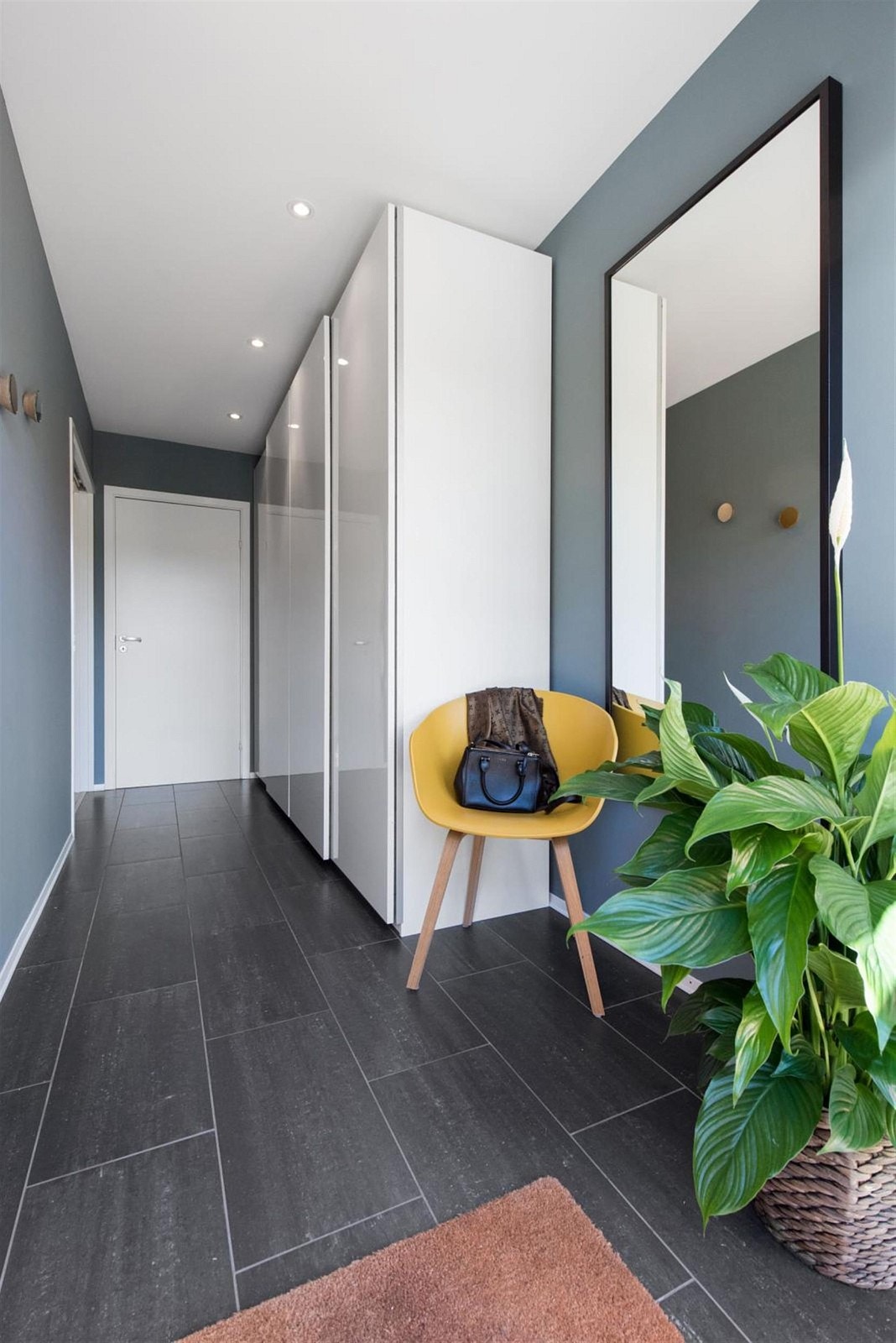 Delikat flislagt entré med stor og praktisk skyvedørsgarderobe. Inngang til bad og vaskerom i enden. Galleribilde