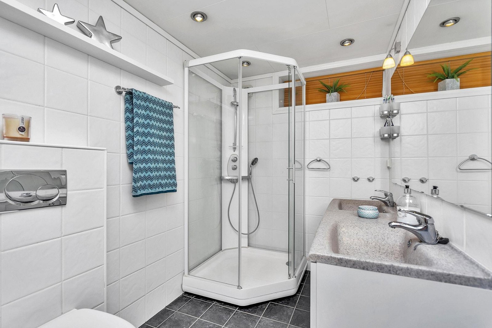 Pent flislagt bad med dusjkabinett, spotter i tak, dobbel servant med underskuff/skap, vegghengt wc, varmekabler i gulv og mekanisk avtrekk. Galleribilde