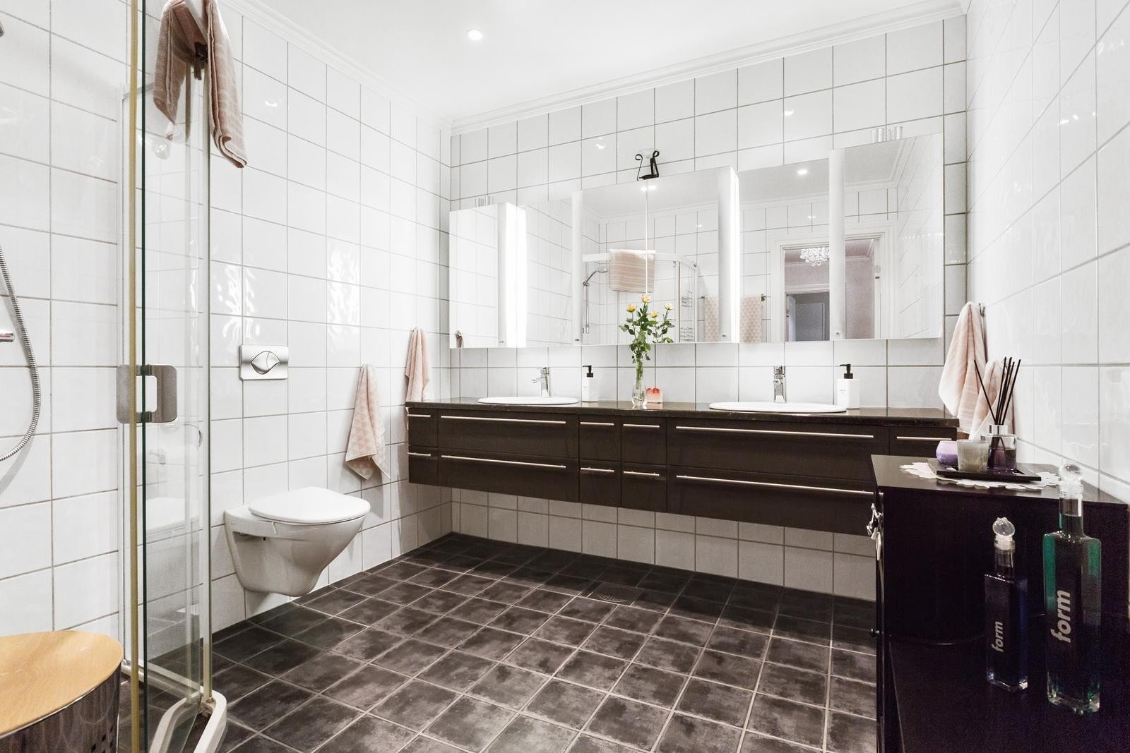 Fra det fliselagte dusjbadet med stor baderomsinnredning med dobbelservant Galleribilde