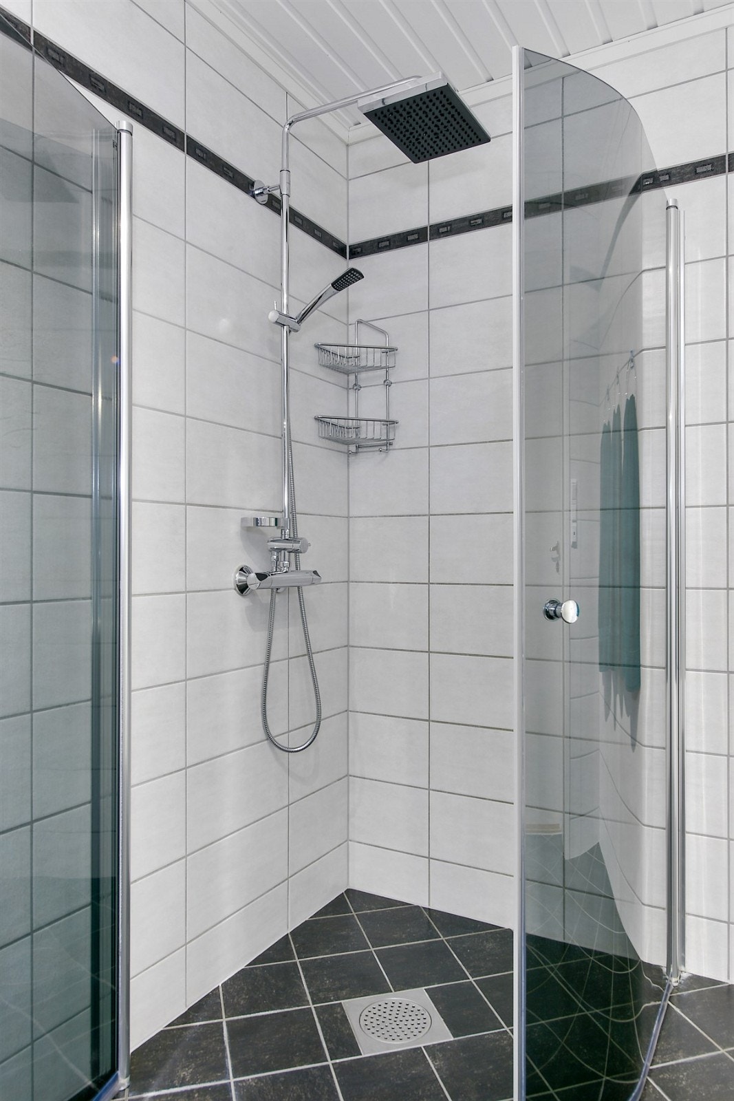 Videre har badet veggmontert toalett, samt et dusjhjørne med buede glassdører og regnfallsdusj. Galleribilde