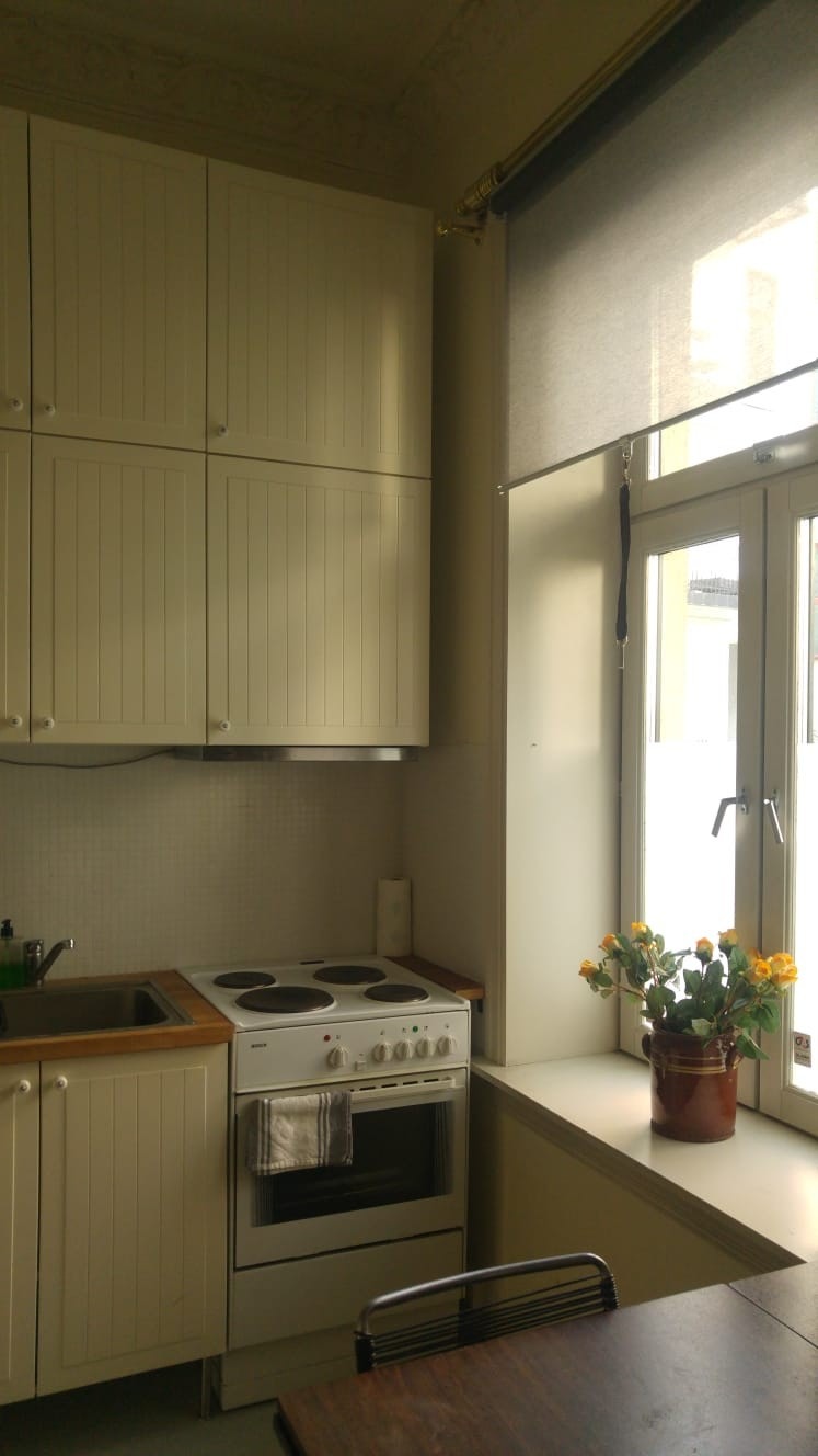 Delen av kjøkkenet nærmest vindu. Kjøleskap under benken lenger til venstre. Galleribilde