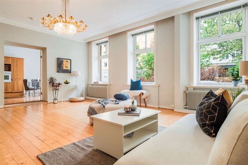 Lys stue med store vinduer og to-fløyet dør inn til kjøkkenet. Galleribilde