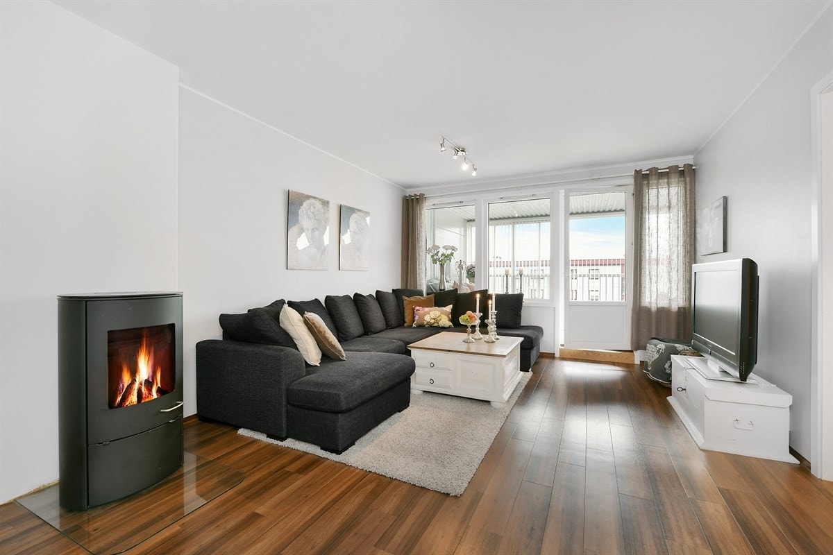 Leiligheten har en smart planløsning og fremstår som lys og innbydende. Stuen har moderne peisovn og god plass til spisebord. Galleribilde