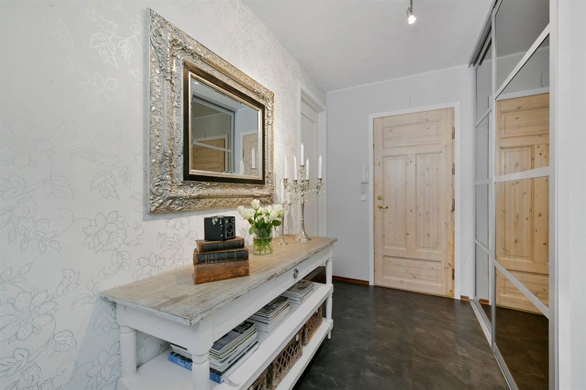 Entreen gir et godt førsteinntrykk av leiligheten og er innredet med grått gulvbelegg og en stor skyvedørsgarderobe med speilfronter. Entreen er holdt i lyse farger noe som er gjennomgående med øvrige rom i leiligheten. Galleribilde
