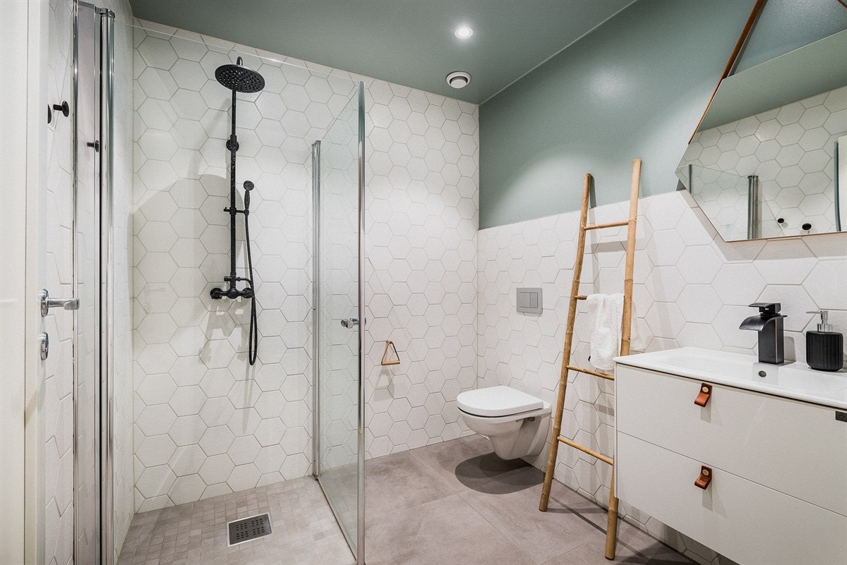 Badet i første etasje er vakkert innredet med sekskantete fliser, regndusj, vegghengt toalett og servant med underskap. Galleribilde