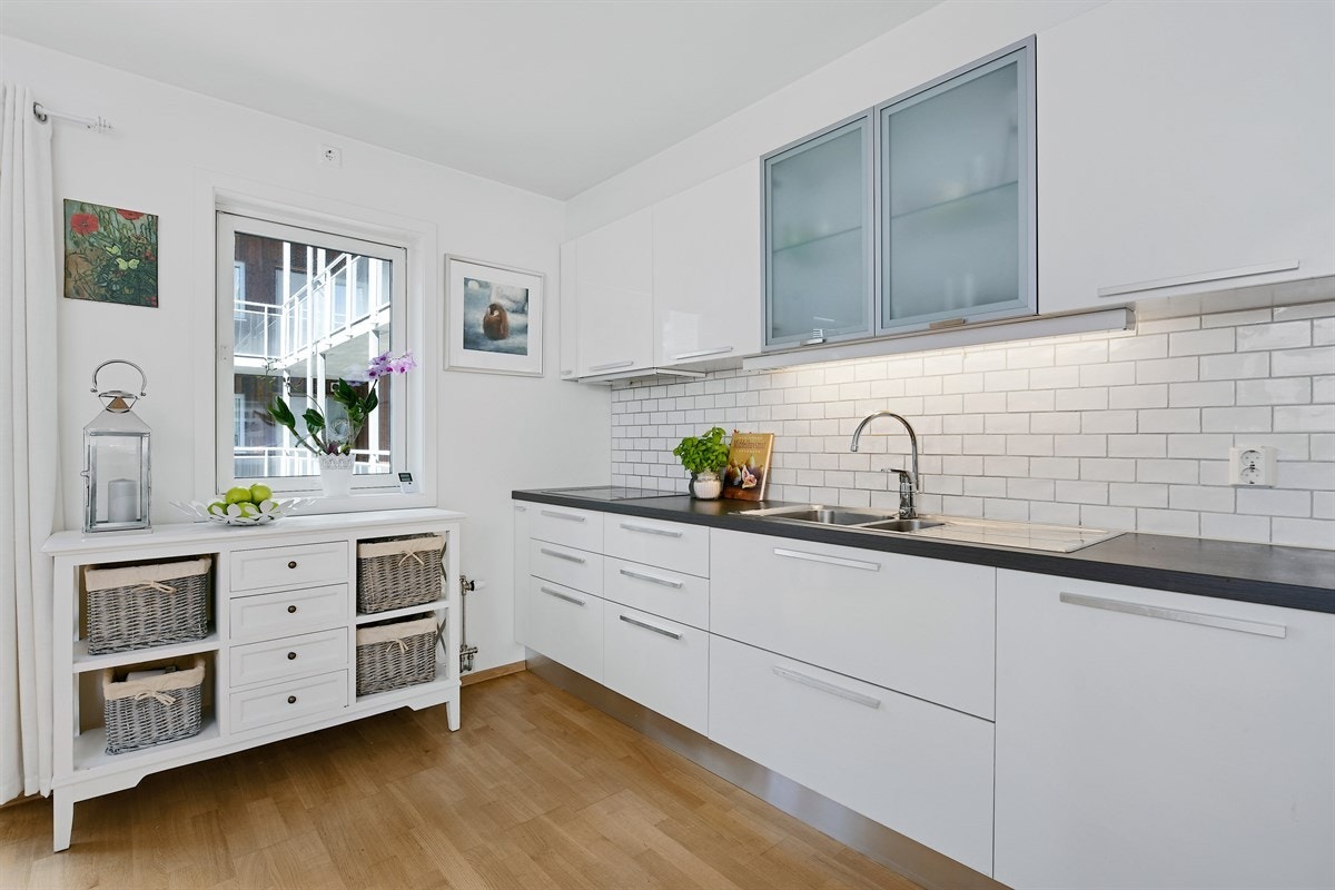 Innredningen består av hvite, lekre høyglansfronter, frostede vitrineskap og mørk benkeplate. Galleribilde