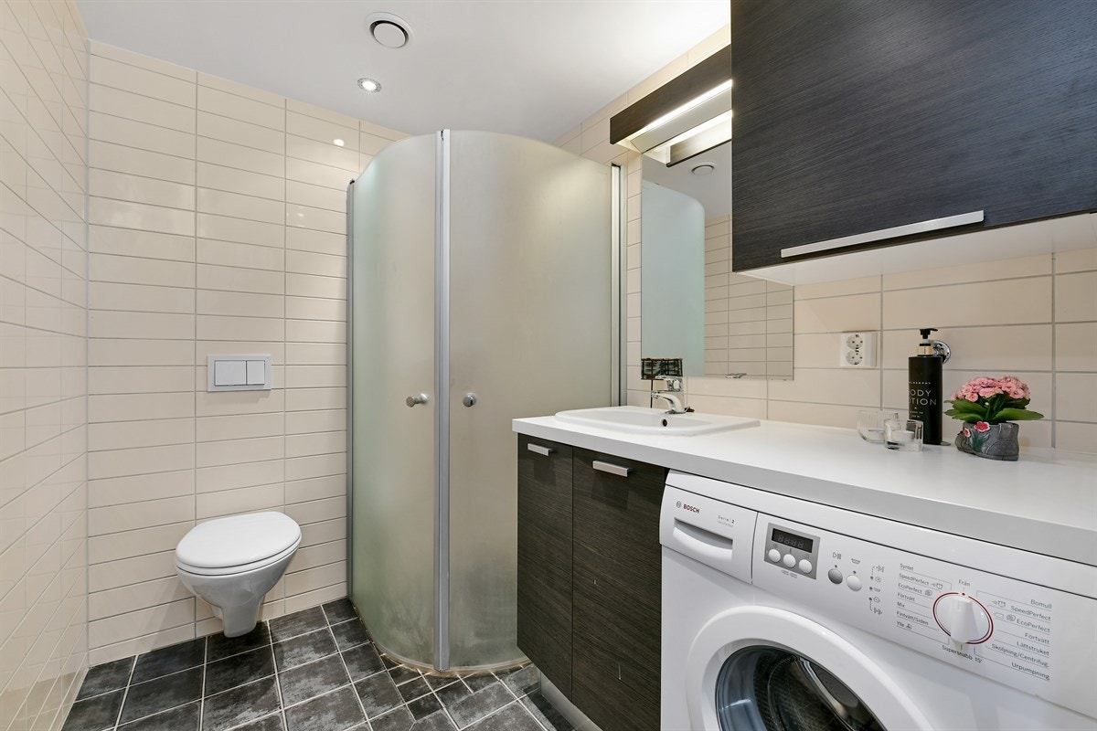 Boligen inneholder et pent bad med vaniljefargede veggfliser og gråmelerte gulvfliser. Galleribilde