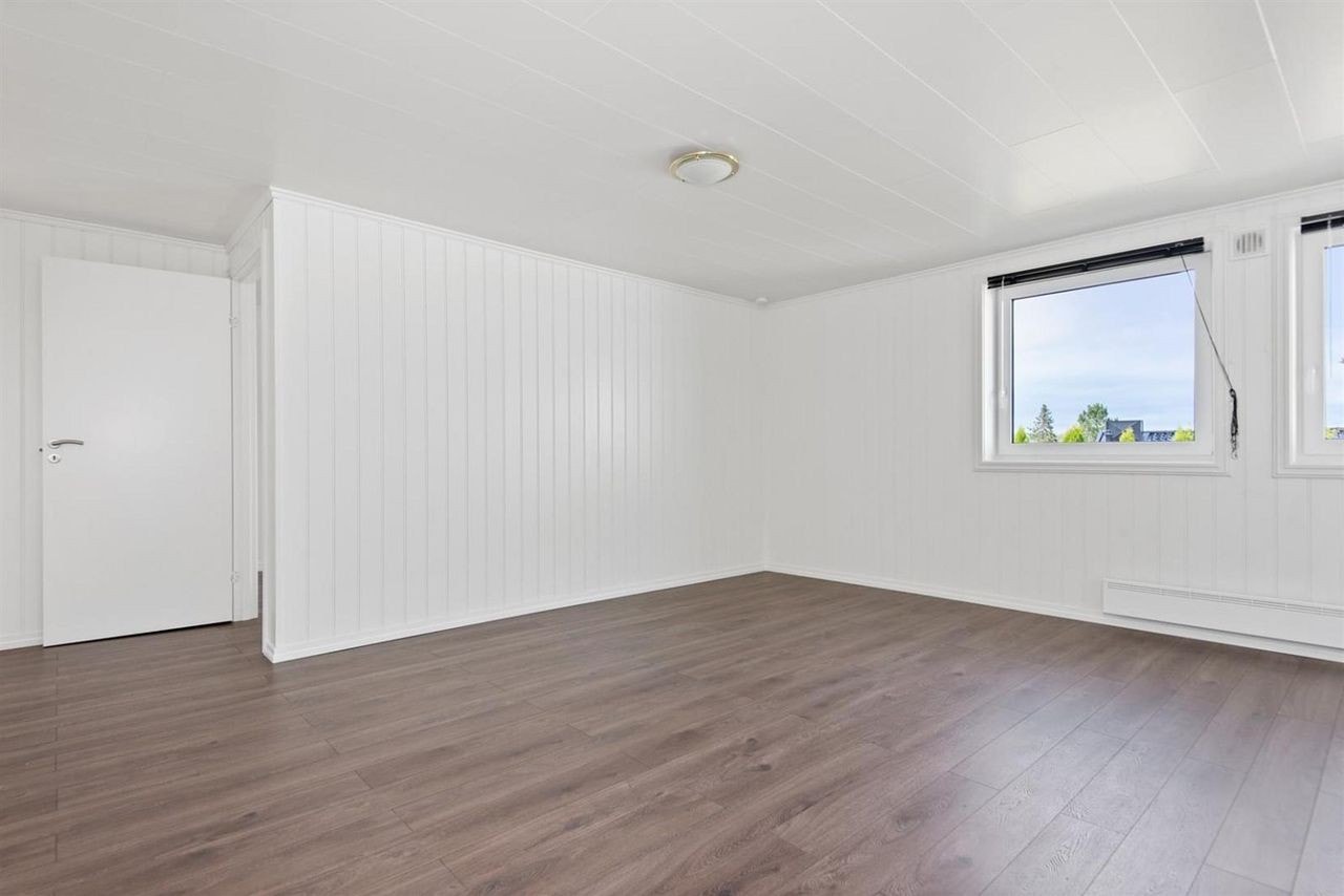 Stua har to vinduer og utsikt til hagen. Det er og panelovn på stua. Galleribilde