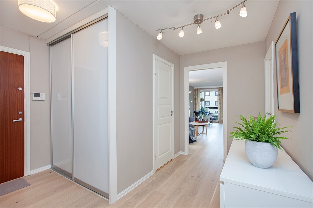 Romslig og lys entré med tilknyttet skyvedørsgarderobe og bod Galleribilde