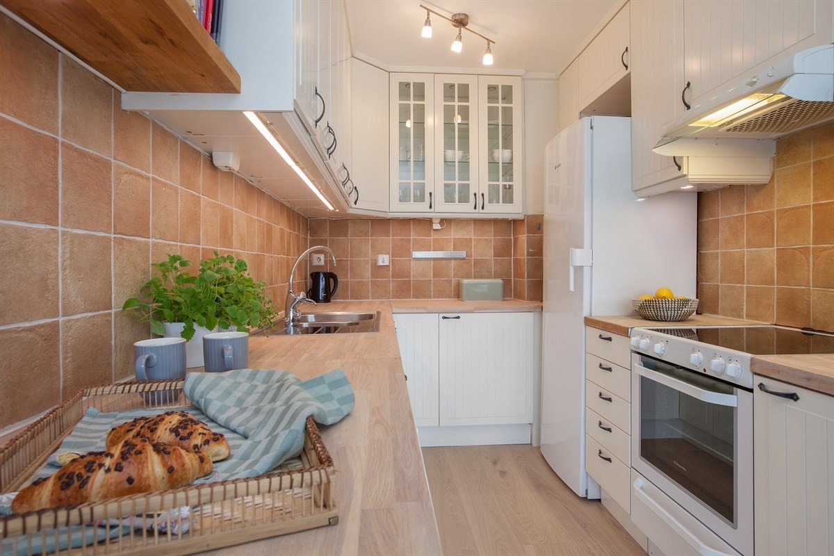 Kjøkkenet har lys og fin innredning med bl.a. tre glassdører i overskap, flott heltre benkeplate og keramiske fliser over kjøkkenbenker m.m Galleribilde