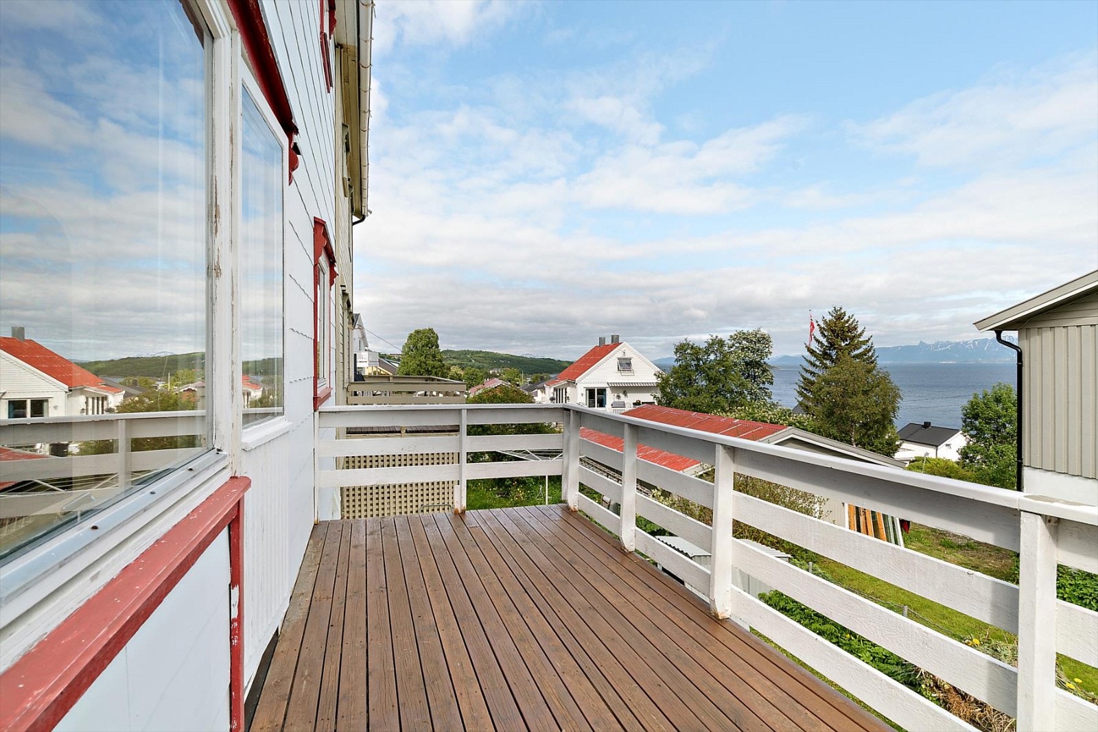 Fra terrasse på nedsiden av boligen er det havutsikt og strålende solforhold på dagtid Galleribilde