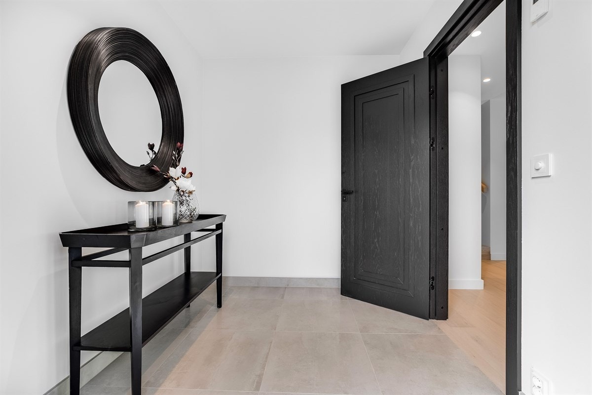 Lys og innbydende entré med 60x60 gulvfliser over vannbåren gulvvarme. Legg merke til den solide designdøren som er gjennomgående i hele boligen! Galleribilde