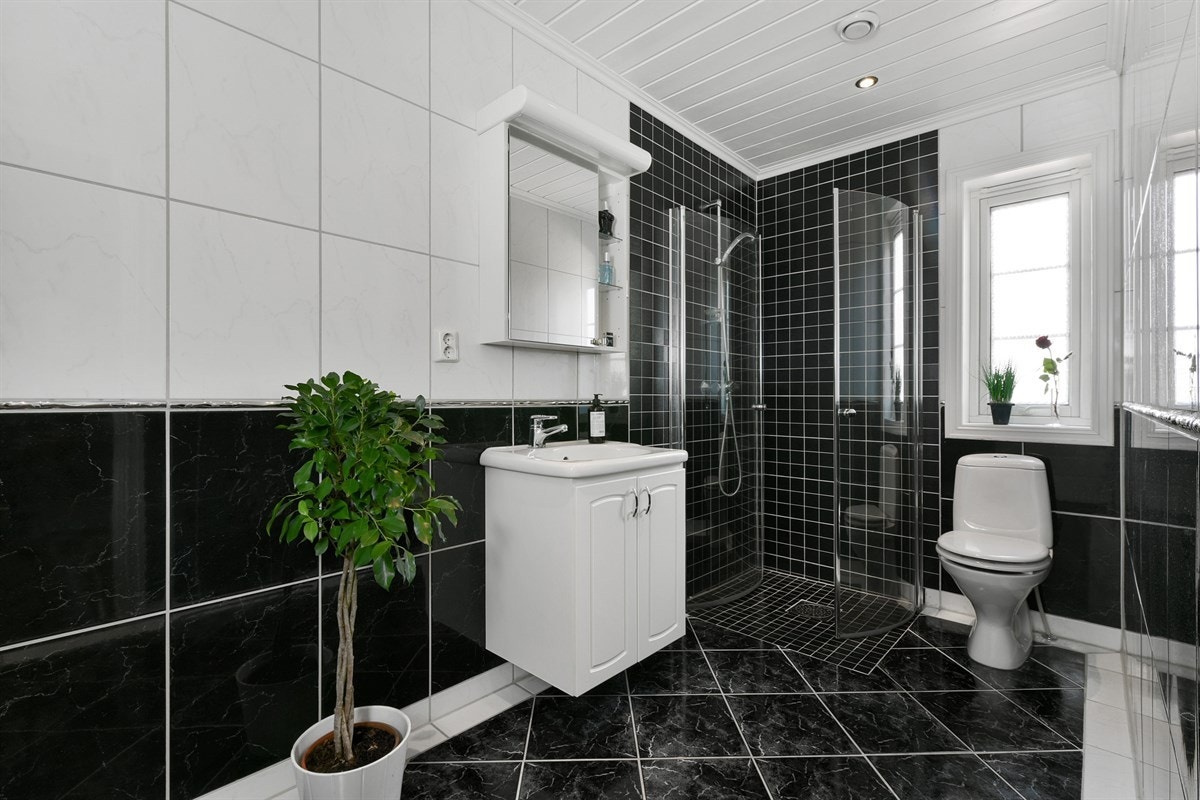 Badet i første etasje har gulv- og veggfliser i sort og hvitt, gulvvarme, downlights, mekanisk avtrekk og frittstående toalett. Galleribilde