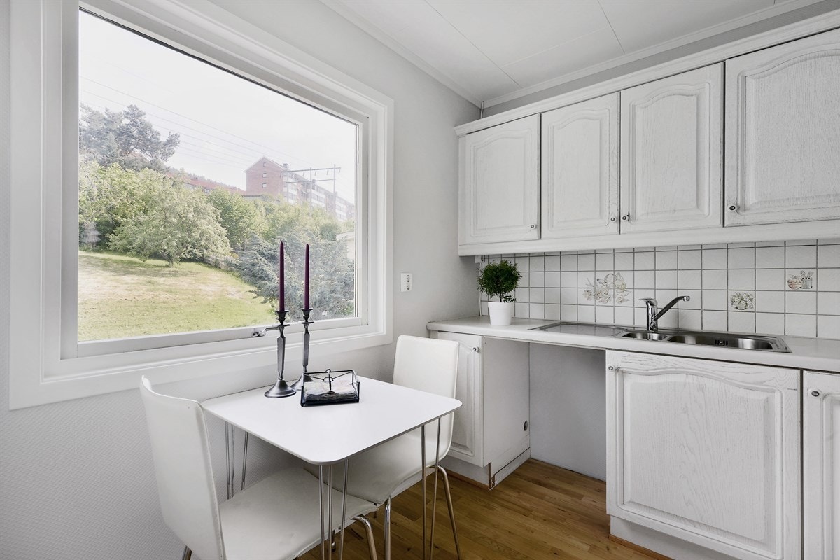 Innredningen har hvite profilerte fronter, vitrineskap og laminert benkeplate med dobbel oppvaskkum. Galleribilde