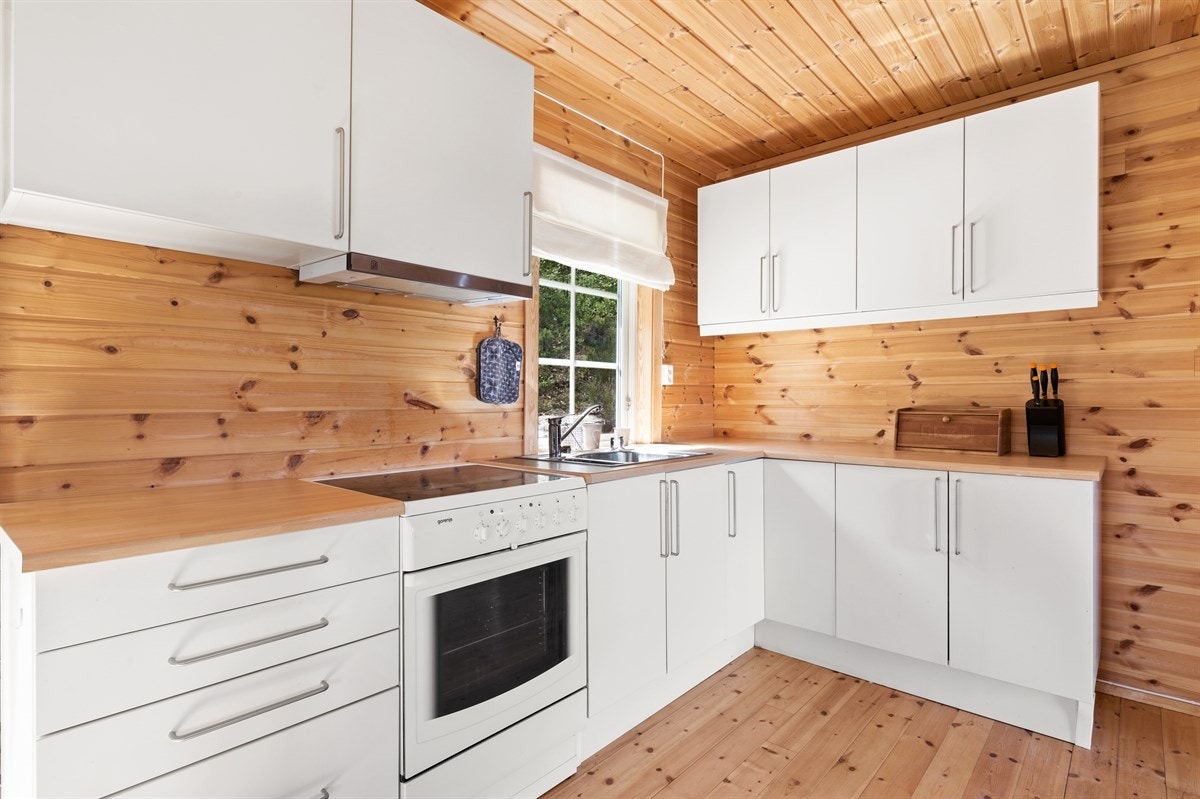 Det er åpen løsning mellom stue og kjøkken. Kjøkkenet består av enkel kjøkkeninnredning med lyse folierte fonter. Galleribilde