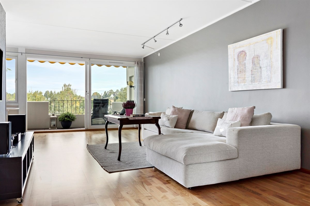 Romslig stue med moderne fargetoner og store vinduer som slipper inn naturlig lys. Galleribilde