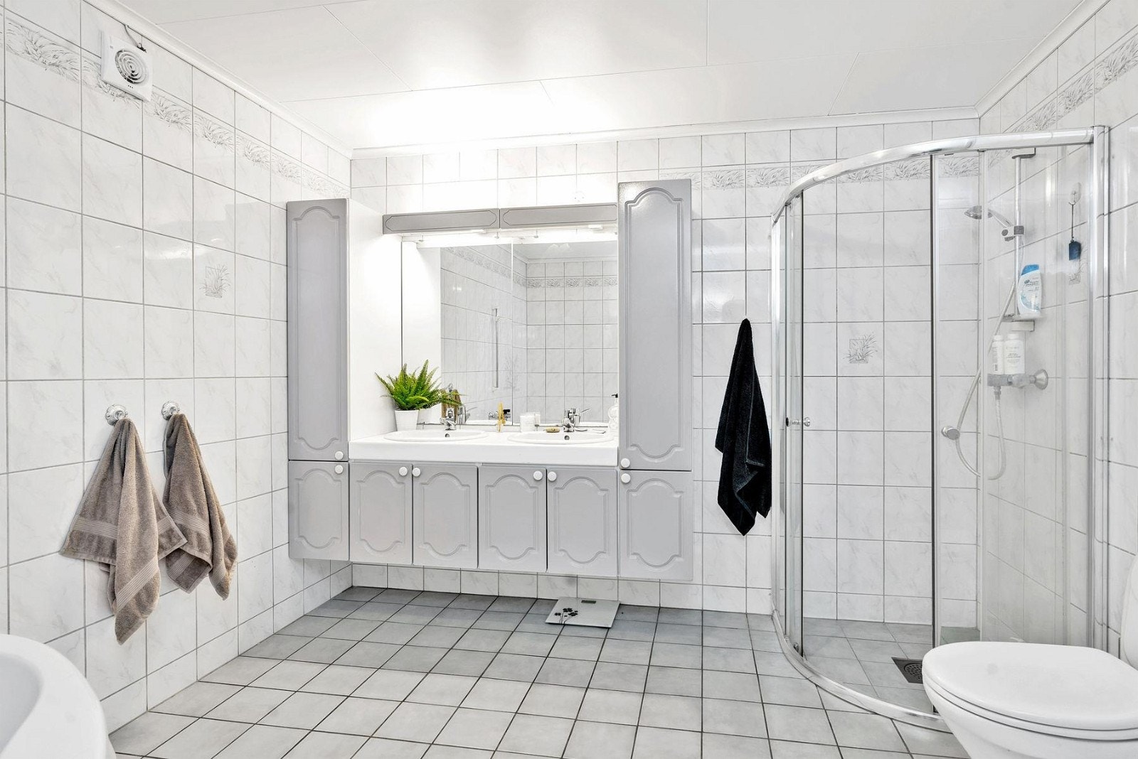 Hovedbadet i underetasjen fremstår som lyst og romslig med fliser på gulv og vegger. Galleribilde