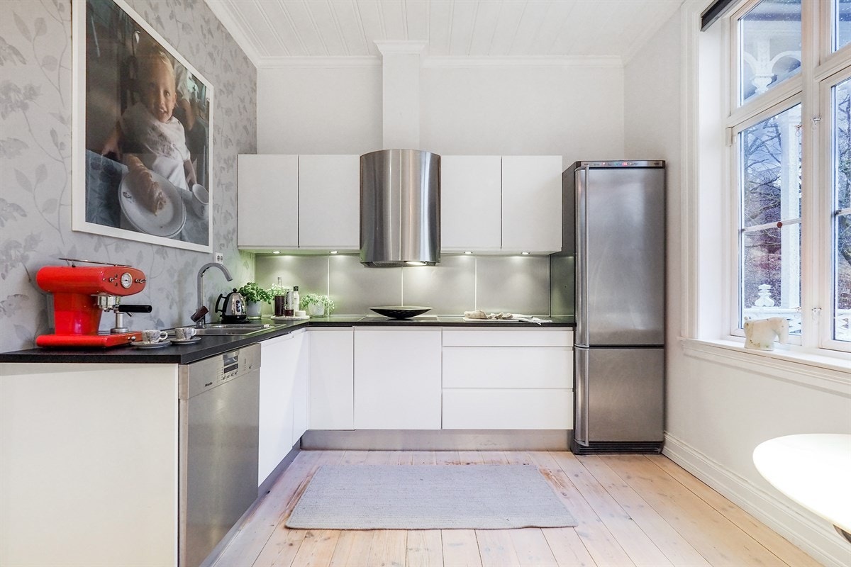 Proaktiv Eiendomsmegling - Det er montert et JKE Design-kjøkken i boligen med hvite, slette fronter og svart laminert benkeplate Galleribilde