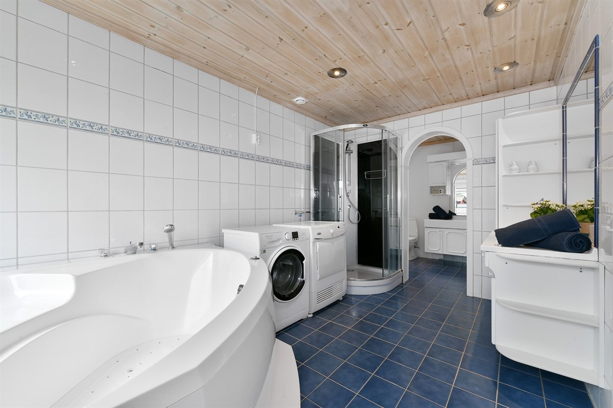 Badet har hvite fliser på veggene, downlights i himling og blå fliser på gulv med gulvvarme. Galleribilde