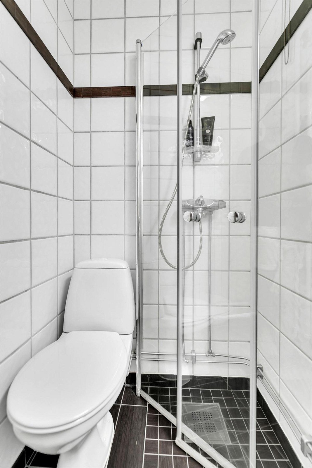 Badet består av servant med skuffeseksjon, speilskap, gulvmontert toalett og dusjnisje med innfellbare dører. Varmekabler i gulvet. Galleribilde