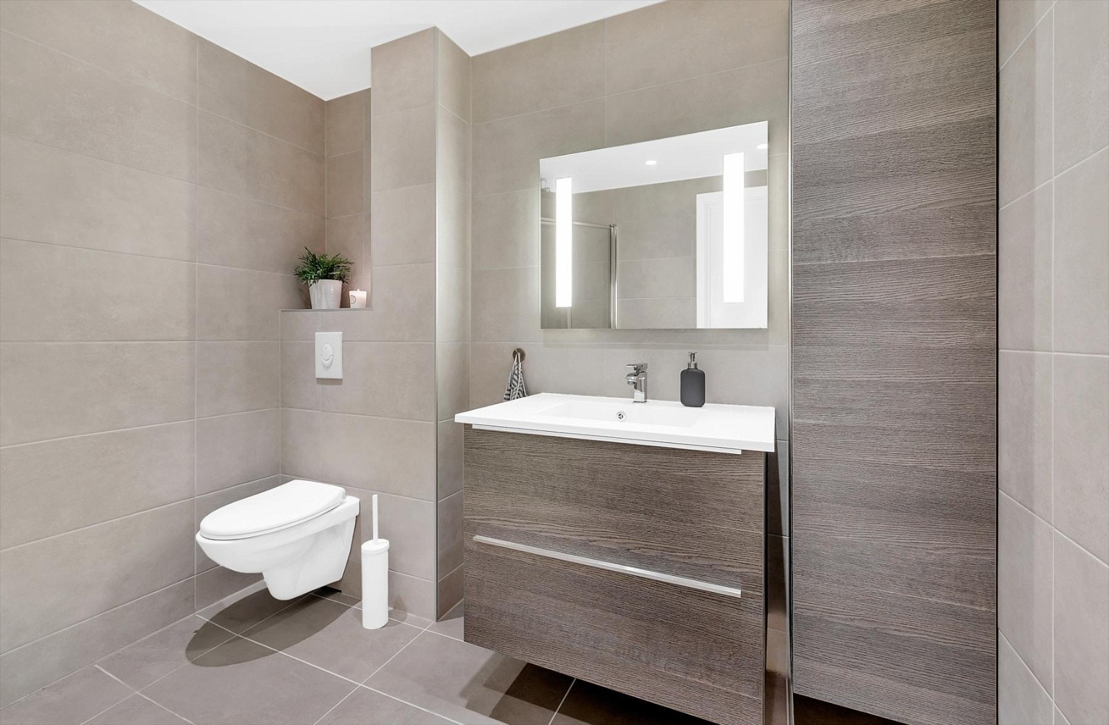 Lekkert bad fra 2014 med vegghengt toalett, servant med baderomsinnredning, speil med lys og skap Galleribilde