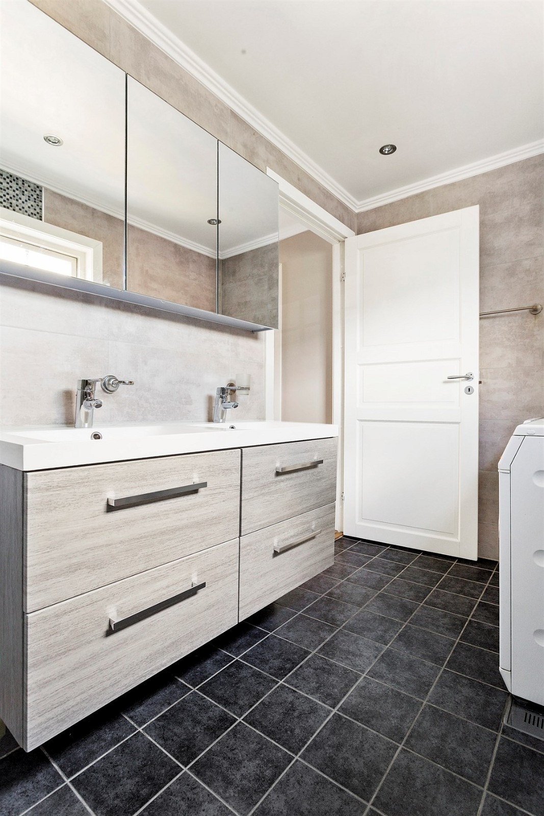 Videre har badet vegghengt klosett, dushjørne med dusjgarnityr av fossefalltype samt opplegg for vaskemaskin og tørketrommel. Galleribilde