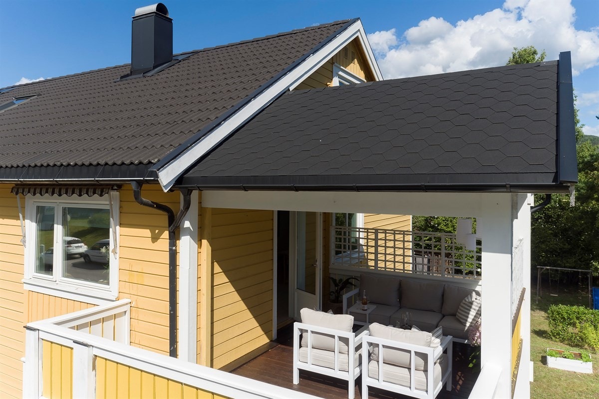 Verandaen har tremmegulv, malt rekkverk i gult og hvitt. Galleribilde