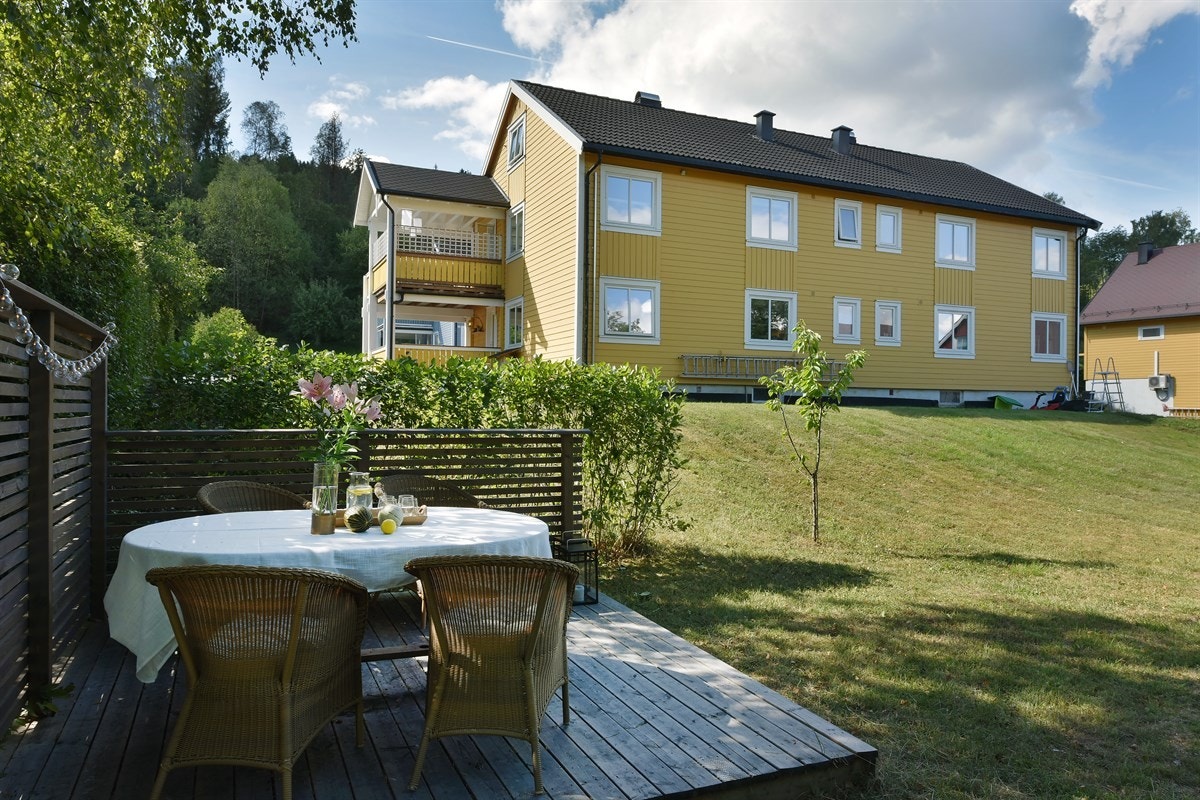 Boligen ligger på romslig fellestomt med delvis omkransende hekk, der det er praktisert at de fire seksjonene disponerer hver sin del av hagen. Galleribilde