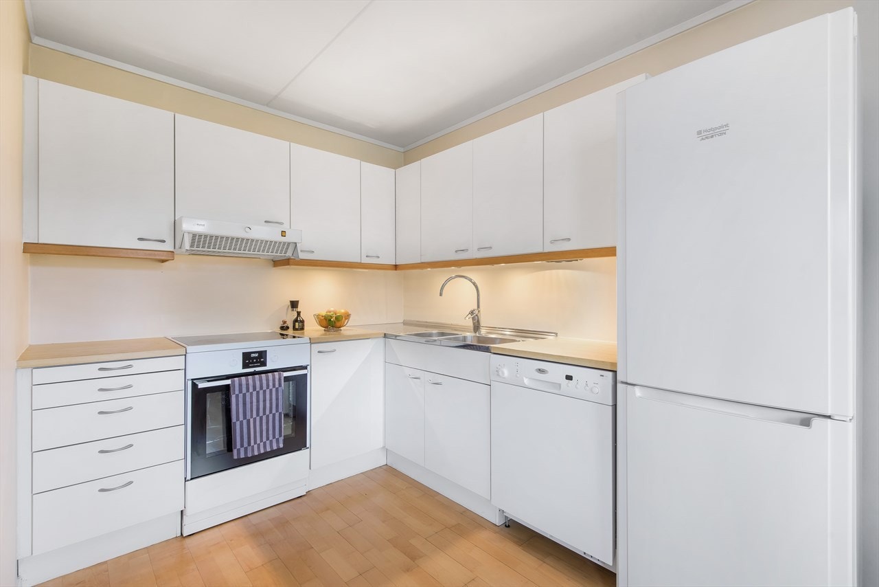 Kjøkkeninnredning med hvite glatte, fronter og benkeplate i laminat Galleribilde