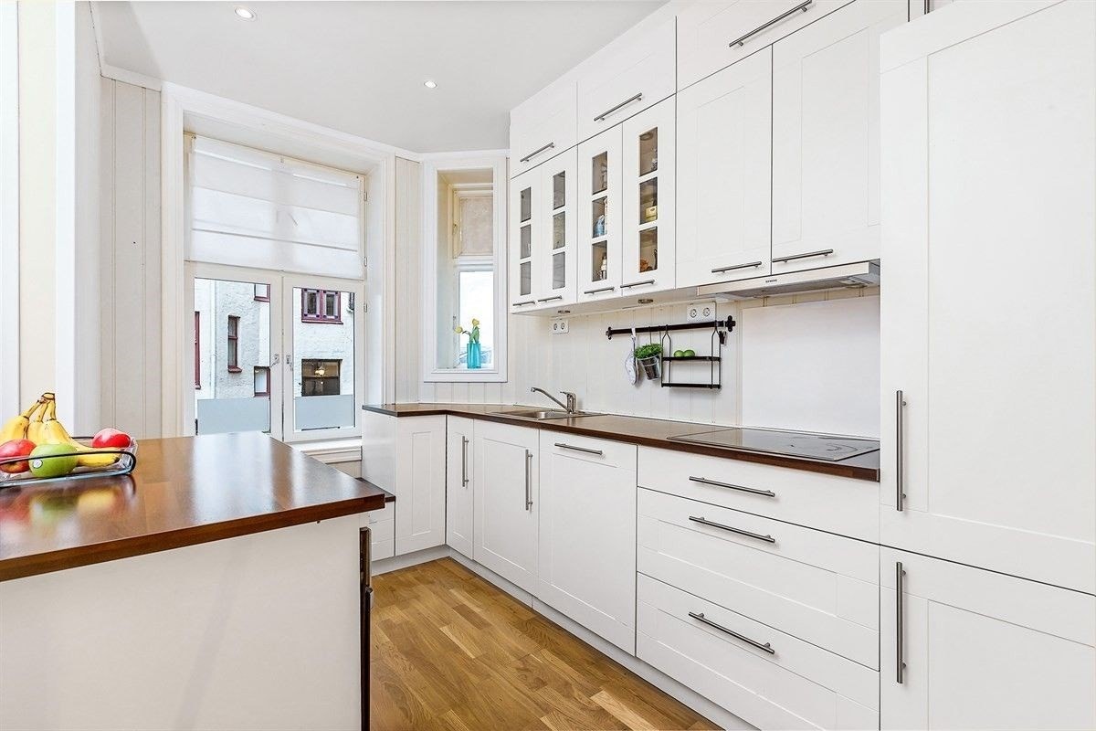 Kvikkjøkken fra 2010 med hvite profilerte fronter og tilhørende kjøkkenøy Galleribilde