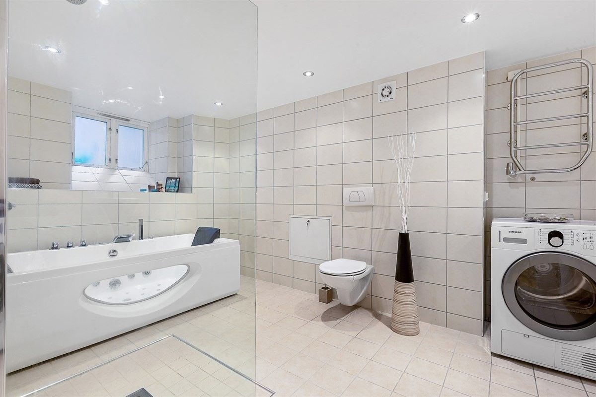 Badet ligger i underetasjen og er delikat flislagt med varmekabler, massasjebadekar og dusjhjørne Galleribilde