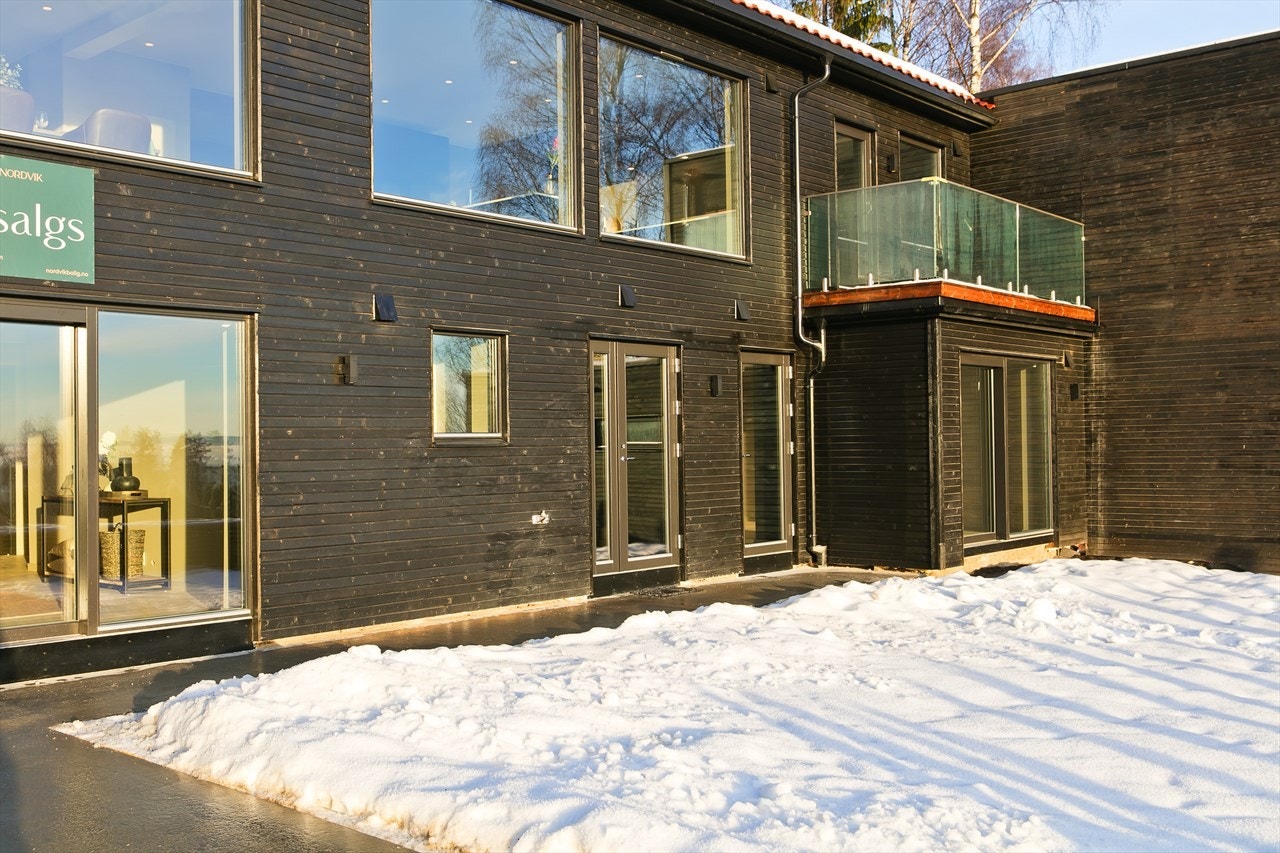 Fra gårdsplassen og garasjen fører en stor og bred trapp med varmekabler opp til hagen, og deretter betongdekke frem til inngangspartiet Galleribilde