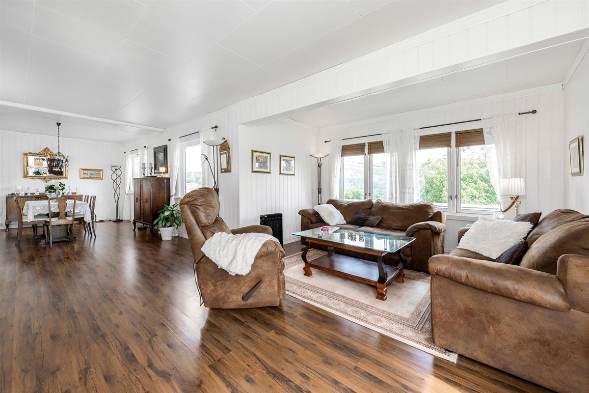 Stuen har parkettgulv, hvitmalt veggpanel og flotte vindusflater som fyller rommet med lys. Galleribilde