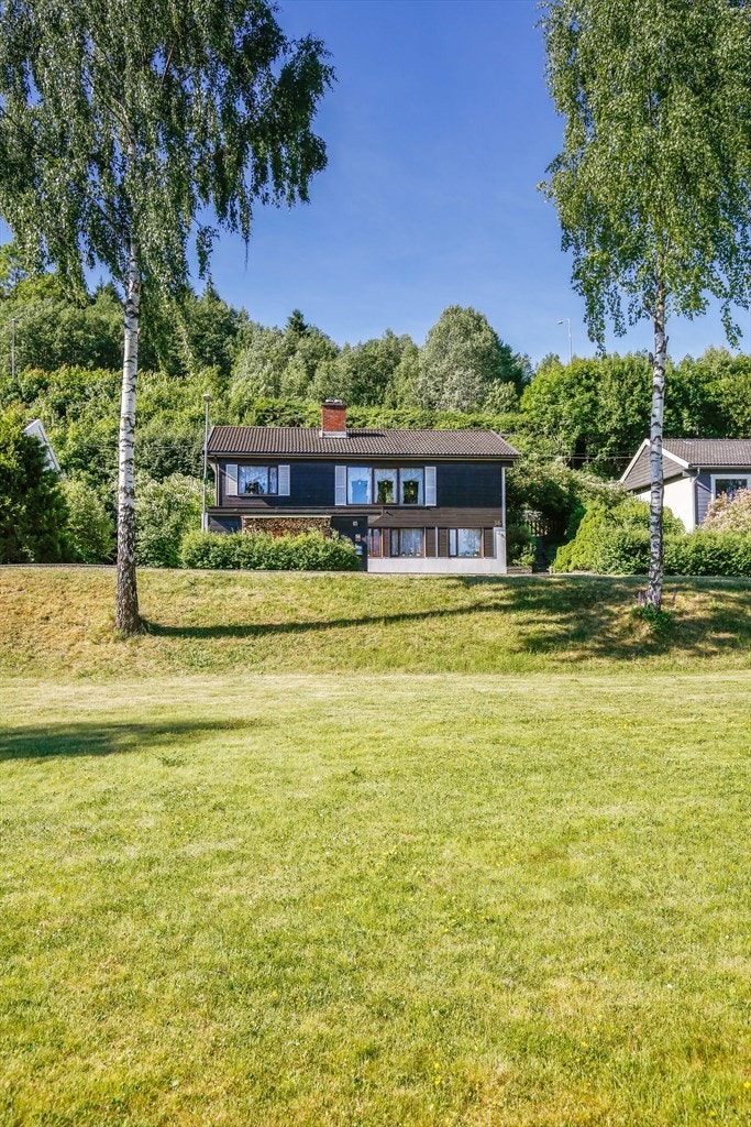 Deler av hagen er avgrenset med et lavt stakittgjerde, og langs siden av huset er en trapp i terrenget. Galleribilde