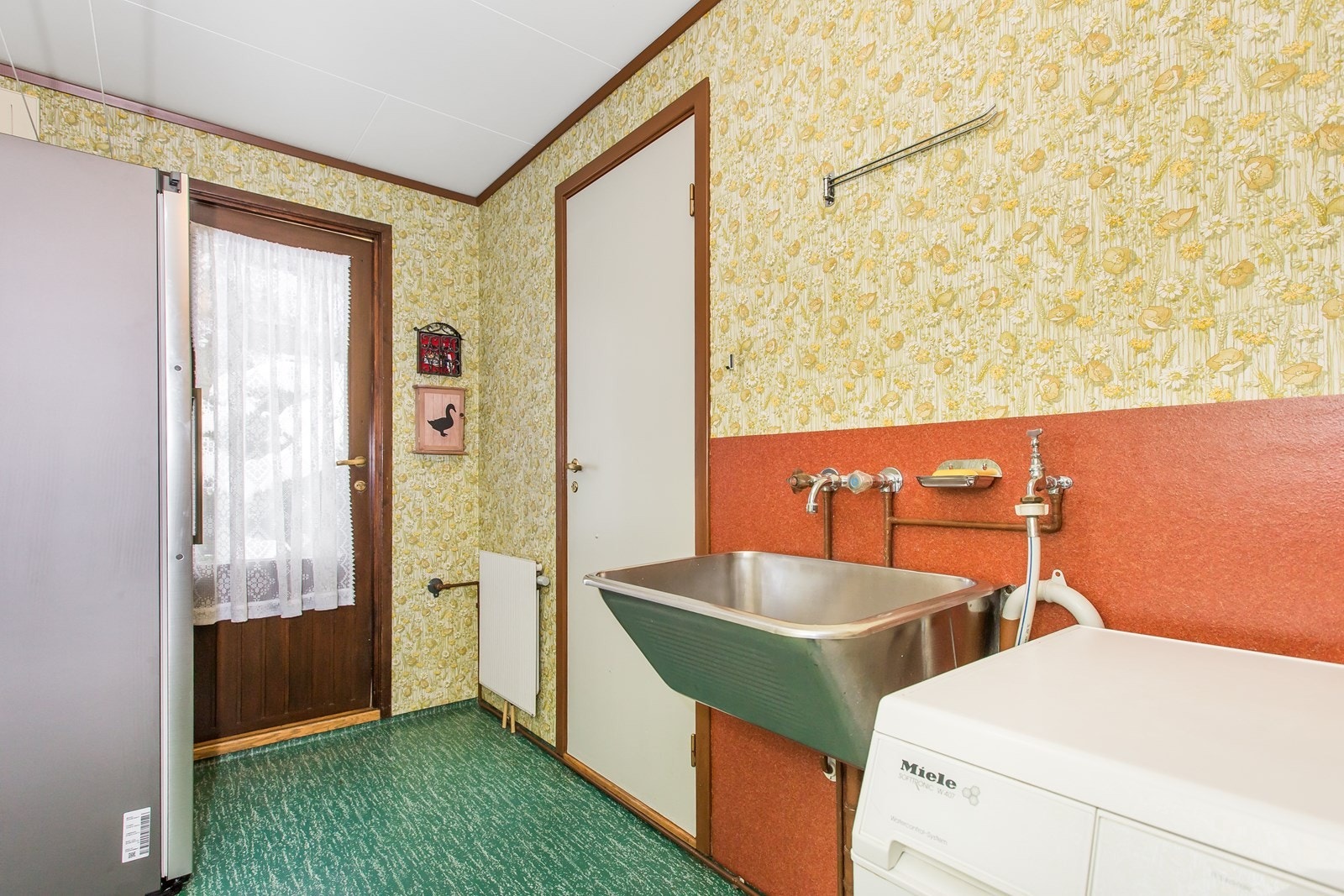 Vaskerommet ligger innenfor kjøkkenet og er utstyrt med en skyllekum i stål, arbeidsbenk og opplegg for vaskemaskin. Galleribilde