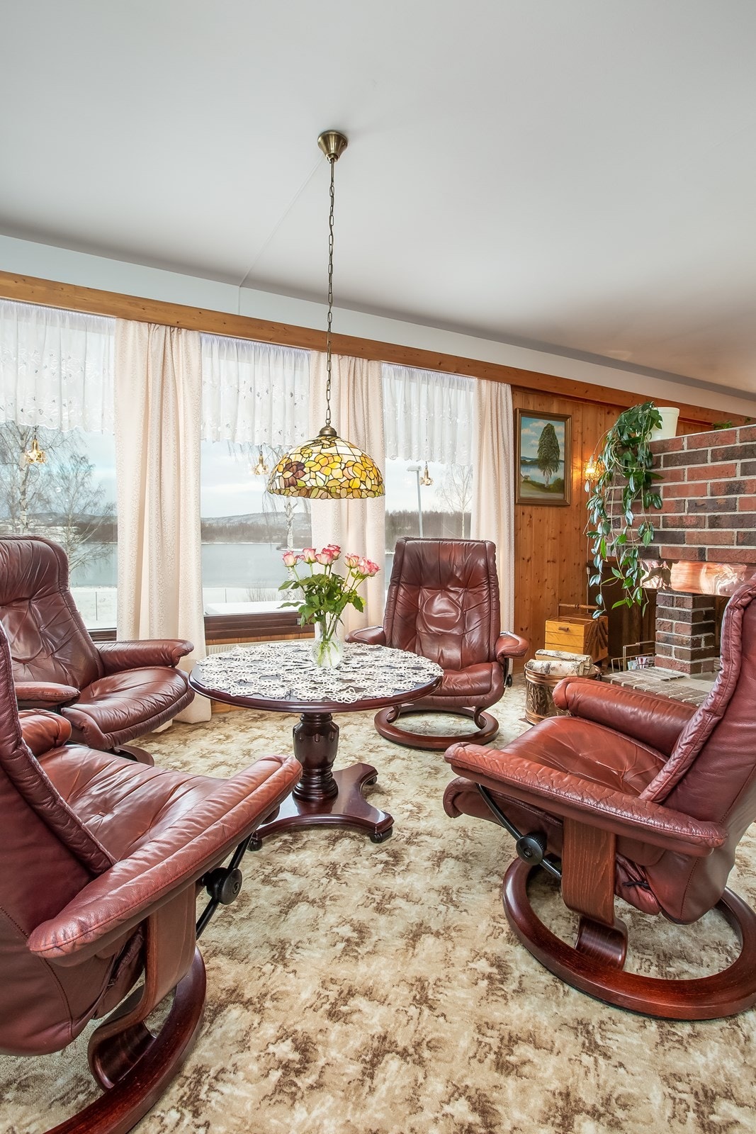 Stuen har kvistpanel og lys tapet på veggen, og mønstret teppegulv. Galleribilde