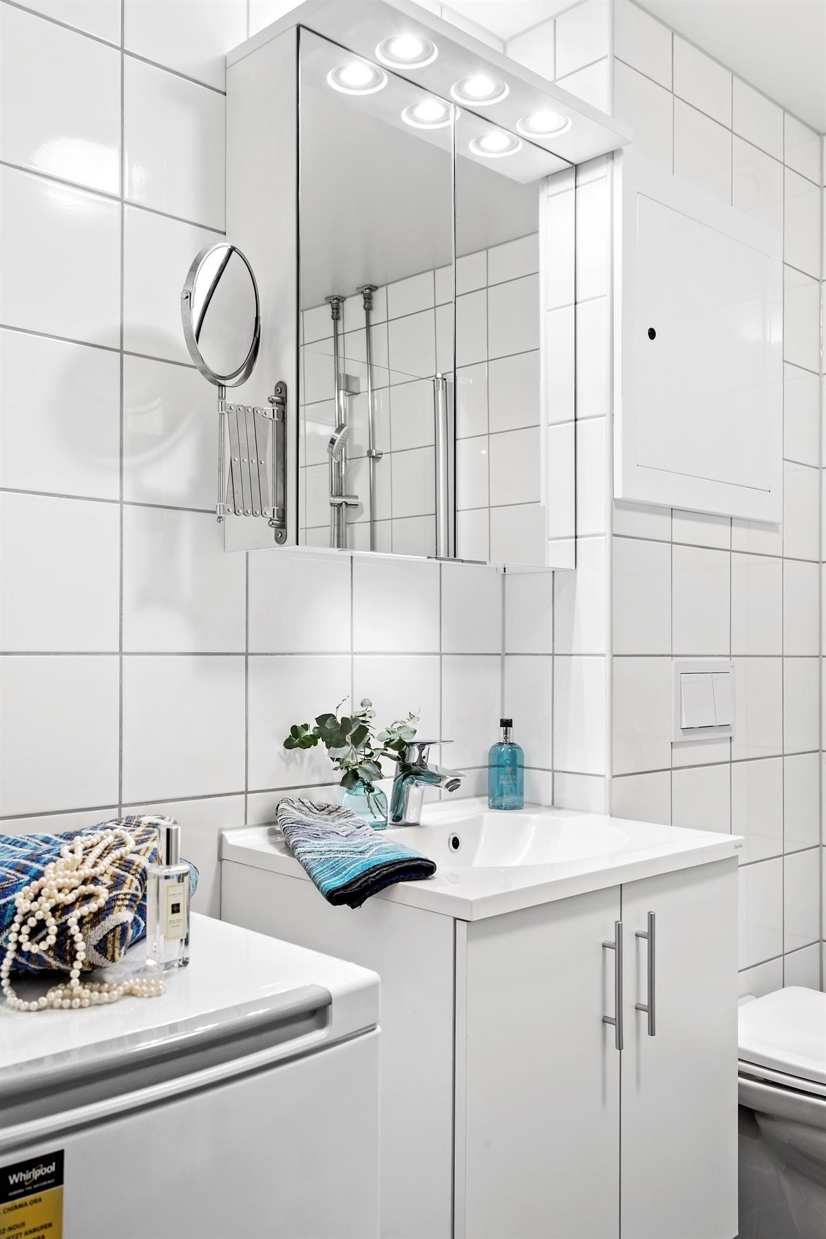 Badet har en svært god størrelse og er utstyrt med åpen dusjplass med slagdører, heldekkende servant i skapinnredning, speilskap, vegghengt wc og opplegg for vaskemaskin. Galleribilde