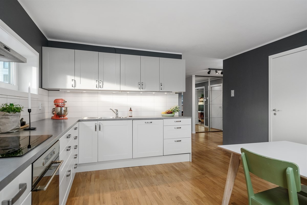 Kjøkkeninnredning har slette hvite fronter, skuffer og skap med demping og laminat benkeplate, Galleribilde