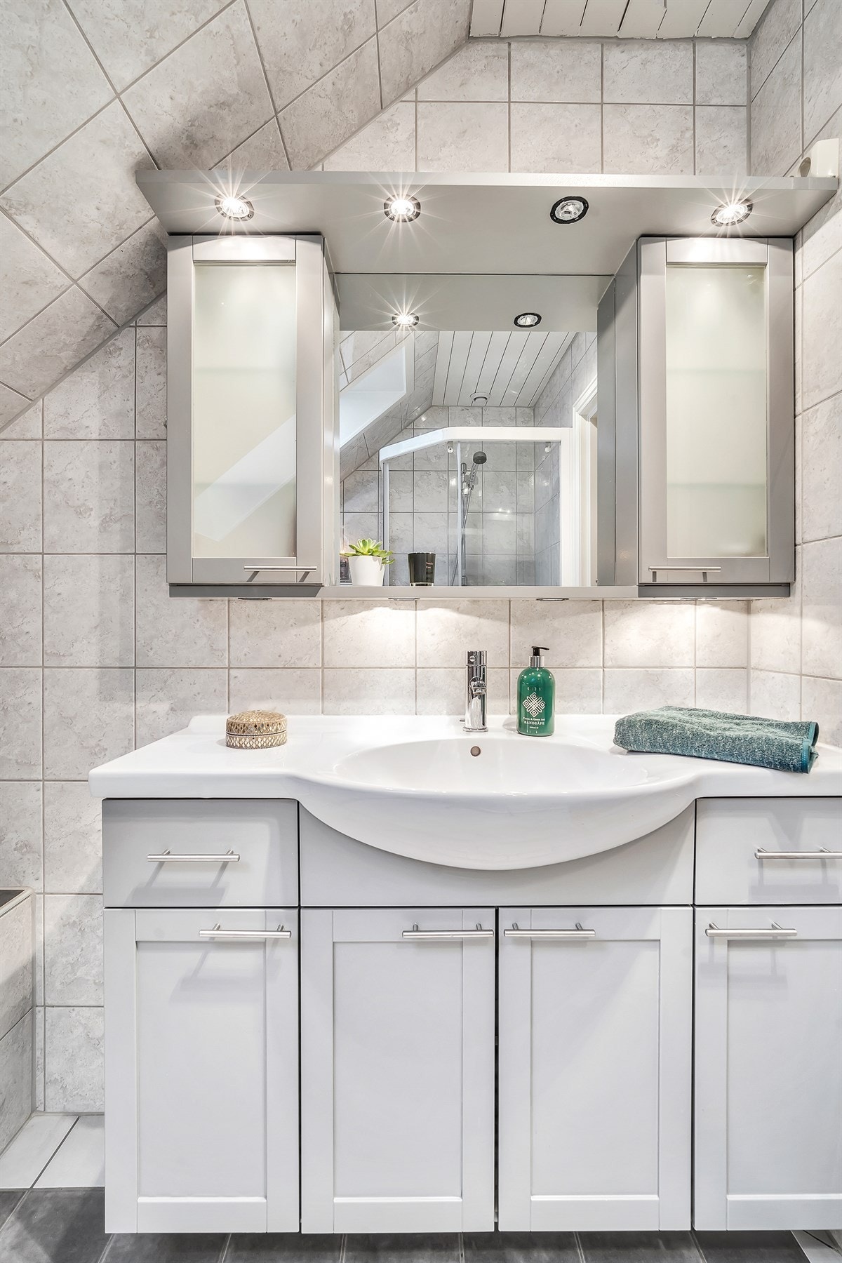 Badet har innredning i lysegrått, vegghengt toalett og dusjhjørne med skyvedør. Galleribilde