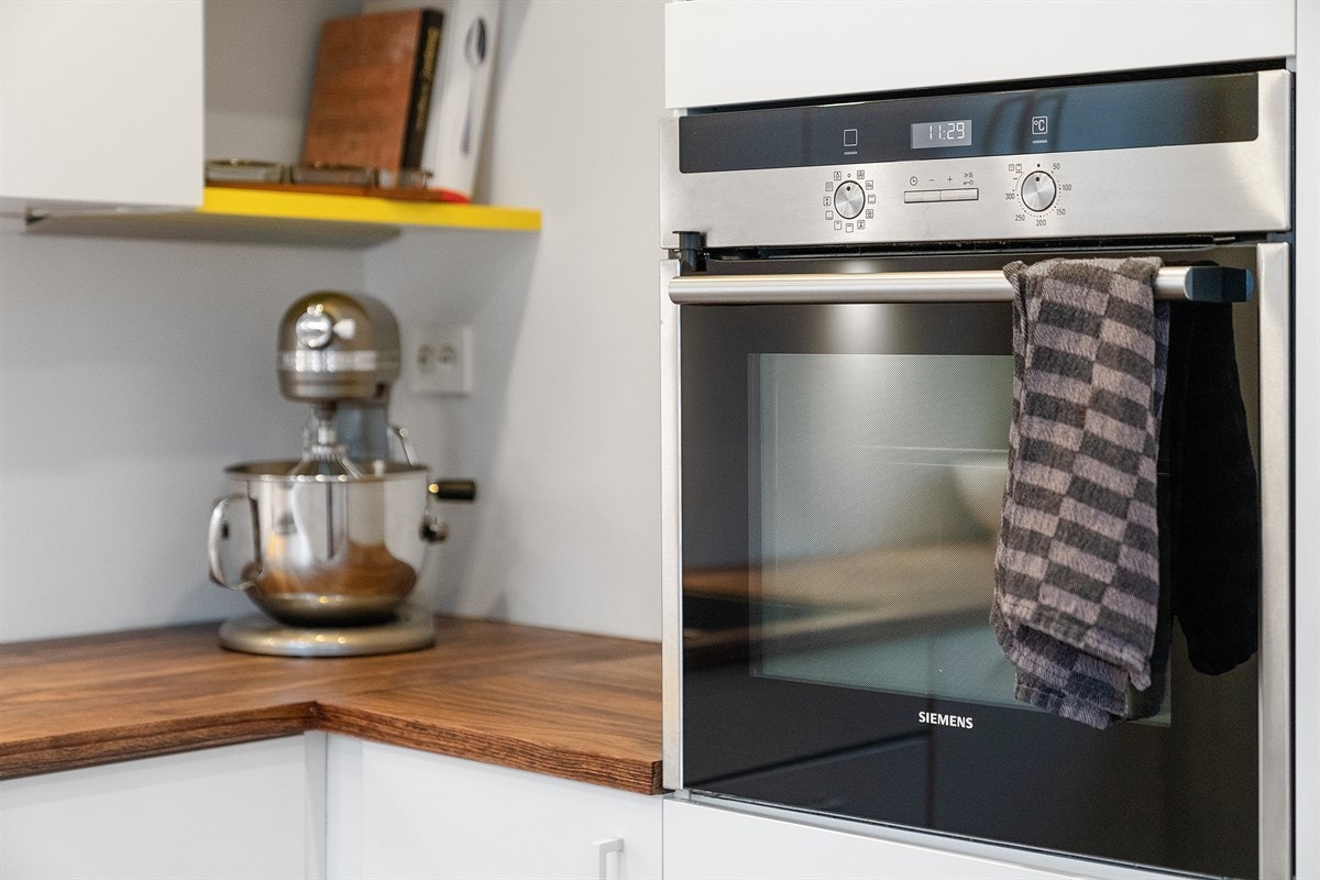 Kjøkkenet består av HTH-kjøkkeninnredning med hvite/glatte fronter, lys under overskap og heltre benkeplater. Galleribilde